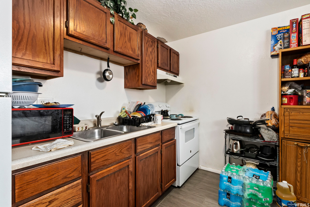 Kitchen with sink, white range with electric cooktop, a textured ceiling, and hardwood / wood-style flooring