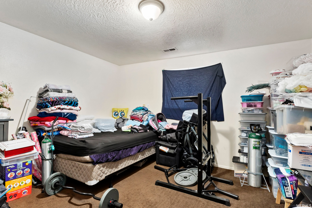 Bedroom featuring dark carpet and a textured ceiling