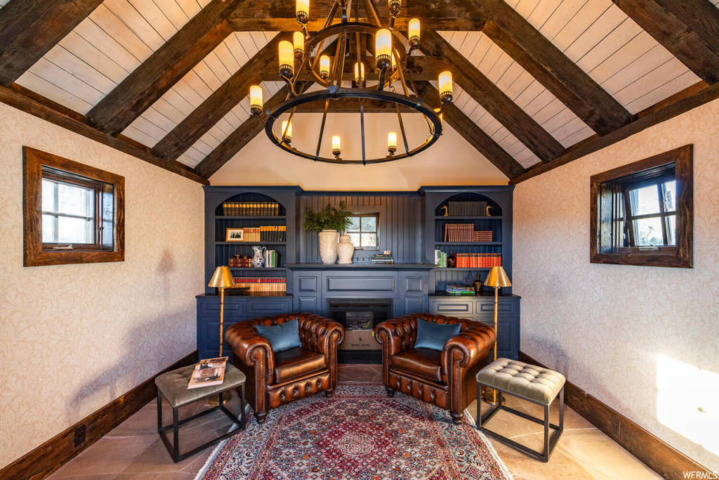 Living area featuring vaulted ceiling with beams, built in shelves, and a chandelier