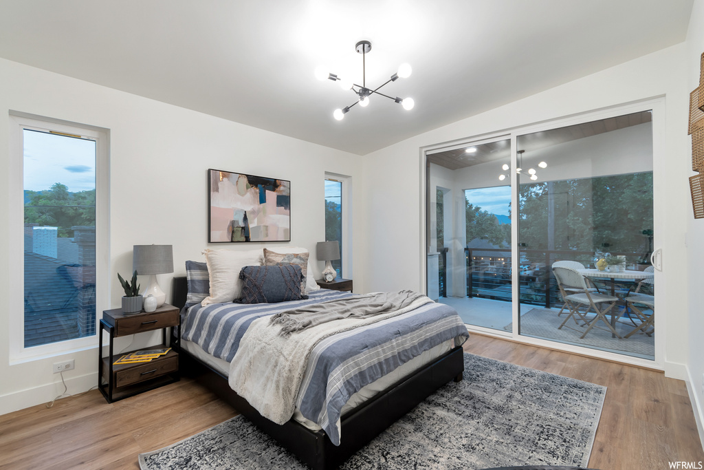 Bedroom featuring access to outside, a notable chandelier, multiple windows, and light hardwood / wood-style floors