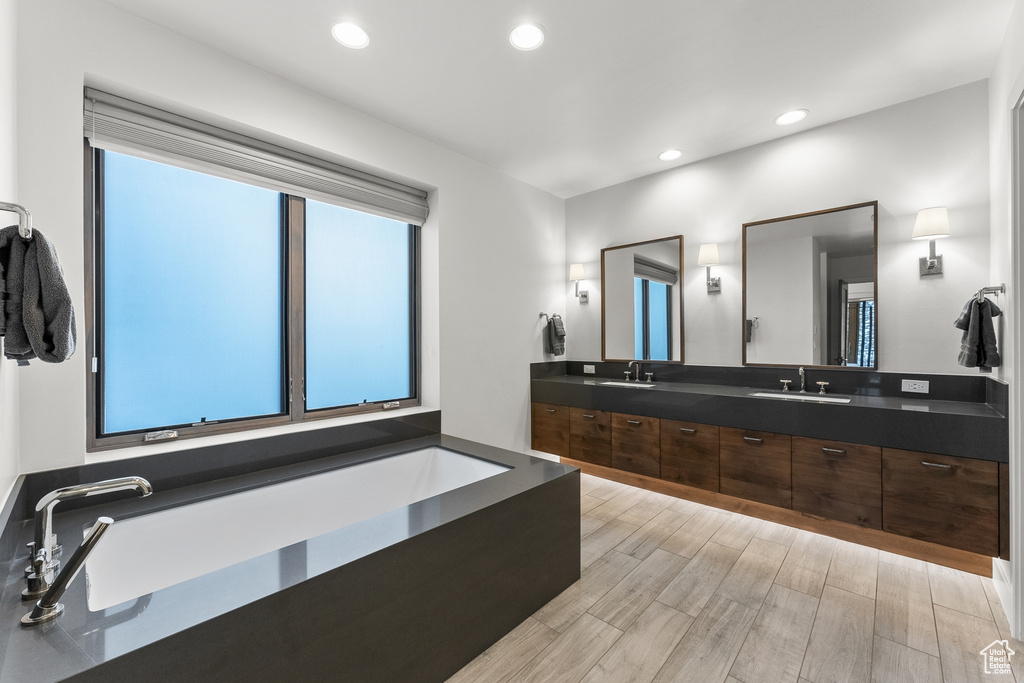 Bathroom with a bathtub, double sink vanity, and hardwood / wood-style flooring