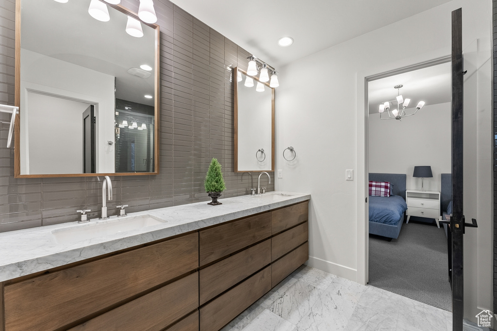 Bathroom featuring tasteful backsplash, tile floors, a notable chandelier, dual vanity, and tile walls