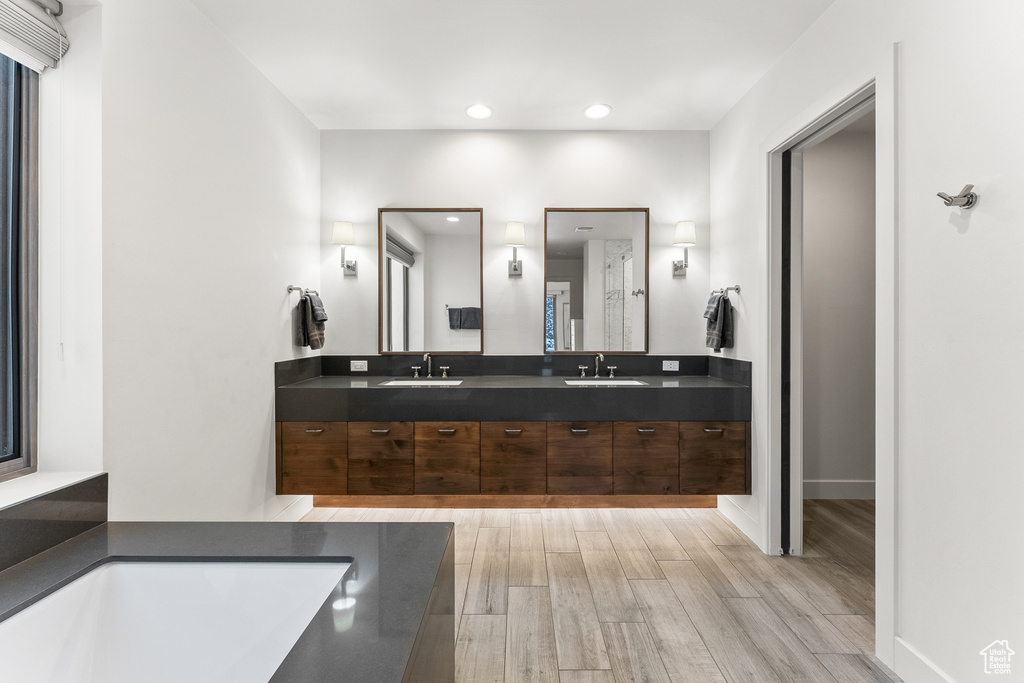 Bathroom with double sink vanity, a bath to relax in, and hardwood / wood-style flooring