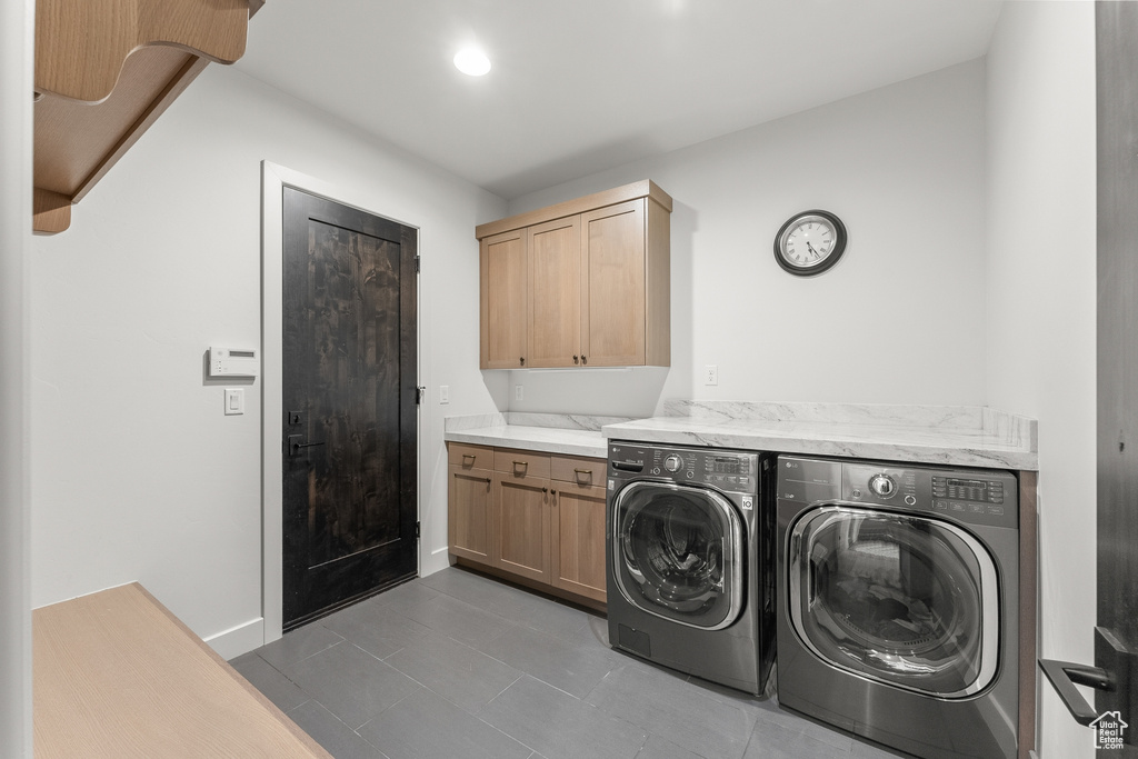Laundry room featuring independent washer and dryer, cabinets, and dark tile floors