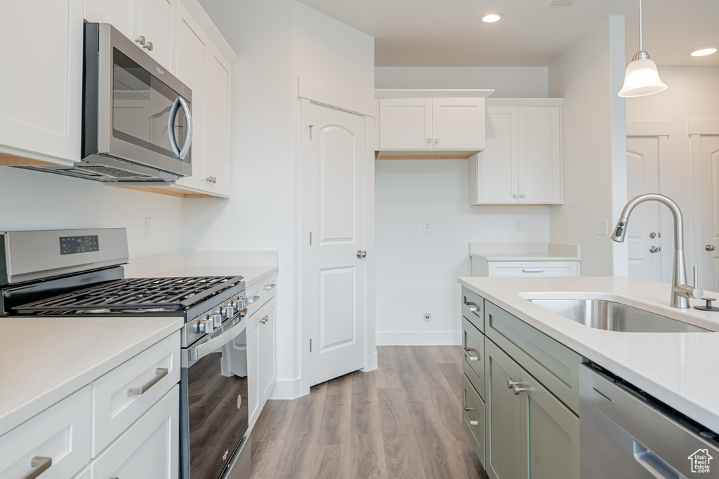 Kitchen featuring white cabinets, sink, stainless steel appliances, and light hardwood / wood-style floors