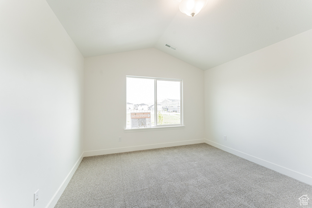 Unfurnished room featuring carpet and lofted ceiling