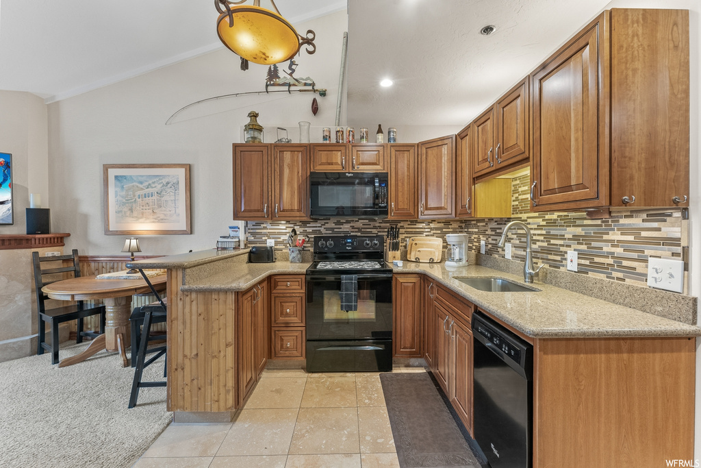 Kitchen with black appliances, light colored carpet, light stone counters, sink, and tasteful backsplash