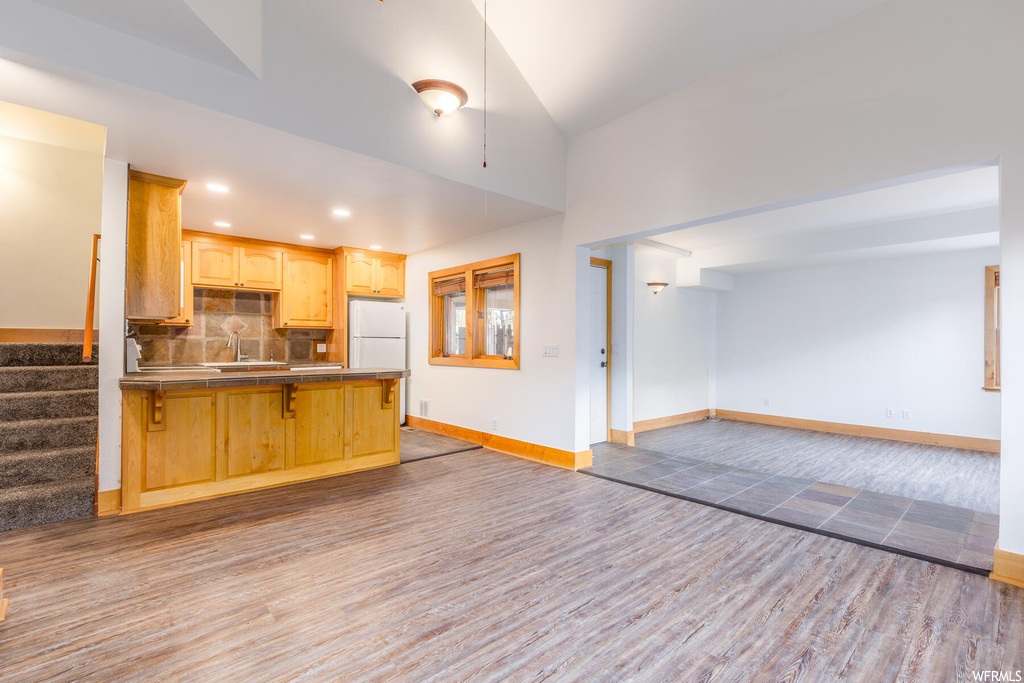 Kitchen with white refrigerator, light brown cabinetry, light hardwood / wood-style floors, and backsplash