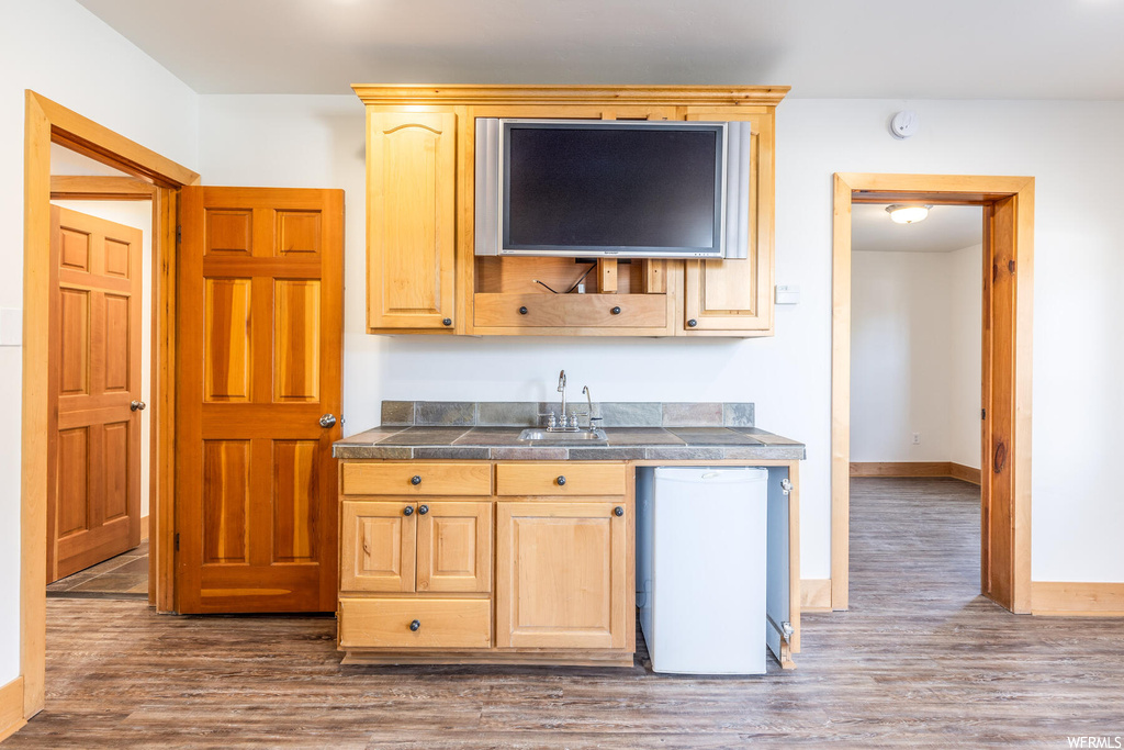 Kitchen featuring light brown cabinets, sink, dishwasher, and hardwood / wood-style flooring
