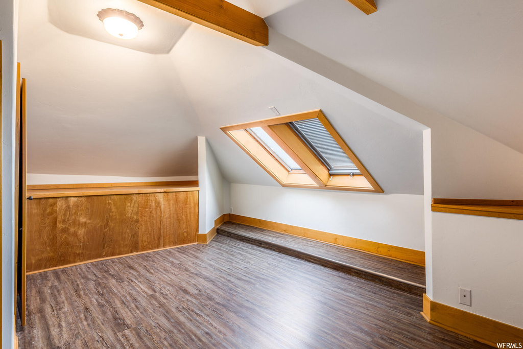 Additional living space featuring lofted ceiling with skylight and dark hardwood / wood-style flooring