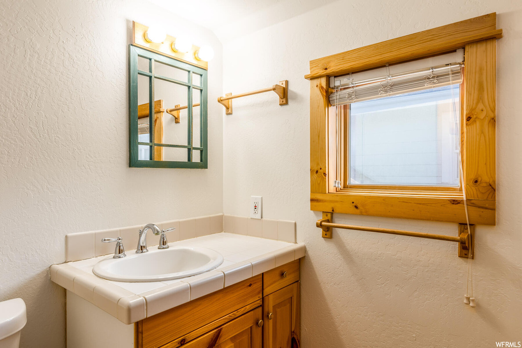 Bathroom featuring toilet, plenty of natural light, and vanity with extensive cabinet space