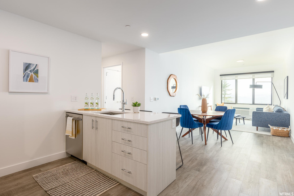 Kitchen featuring stainless steel dishwasher, sink, light hardwood / wood-style flooring, and kitchen peninsula