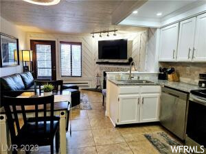 Kitchen with light tile floors, sink, dishwasher, electric range, and white cabinetry