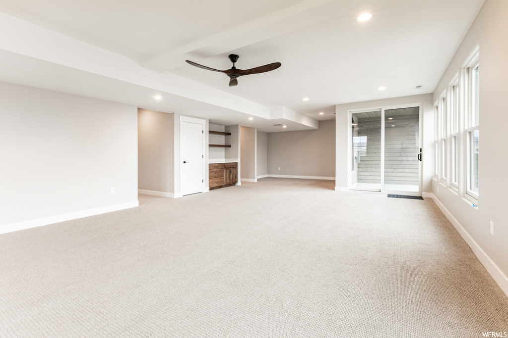 Unfurnished living room featuring light carpet and ceiling fan