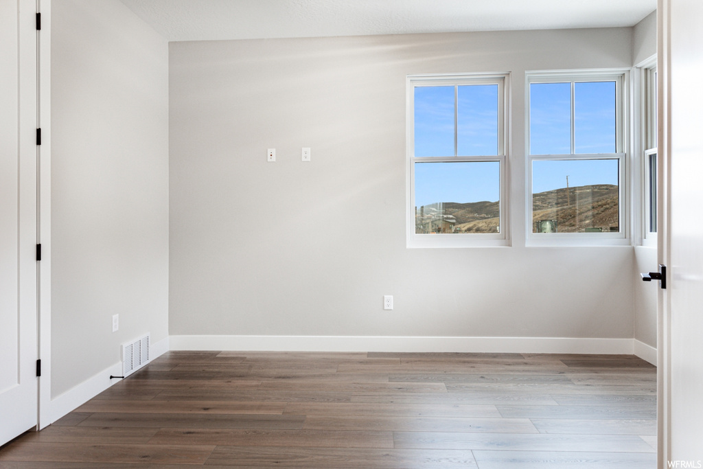 Empty room with plenty of natural light and hardwood / wood-style floors