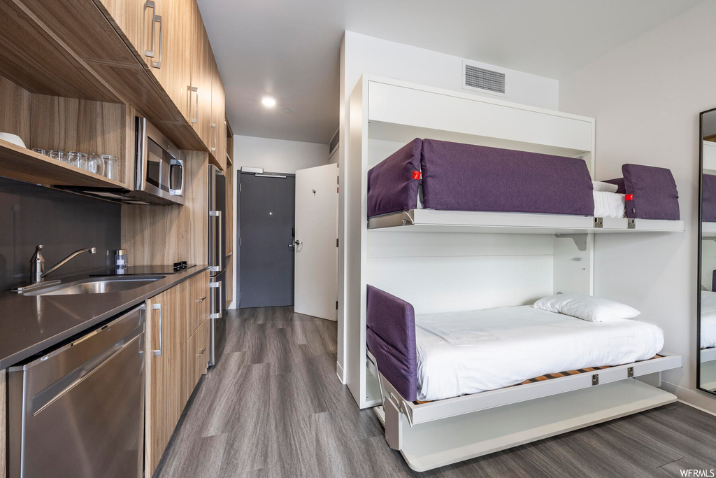Bedroom with dark hardwood / wood-style flooring, high end refrigerator, and sink
