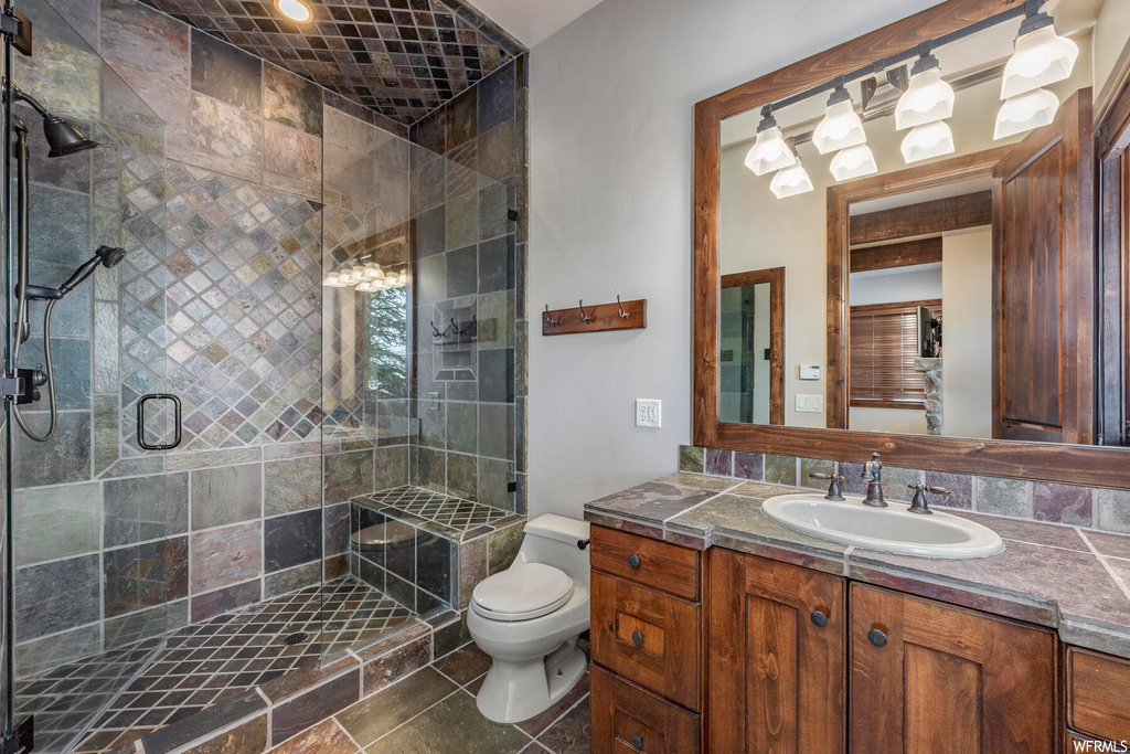 Bathroom featuring oversized vanity, toilet, tile flooring, and an enclosed shower