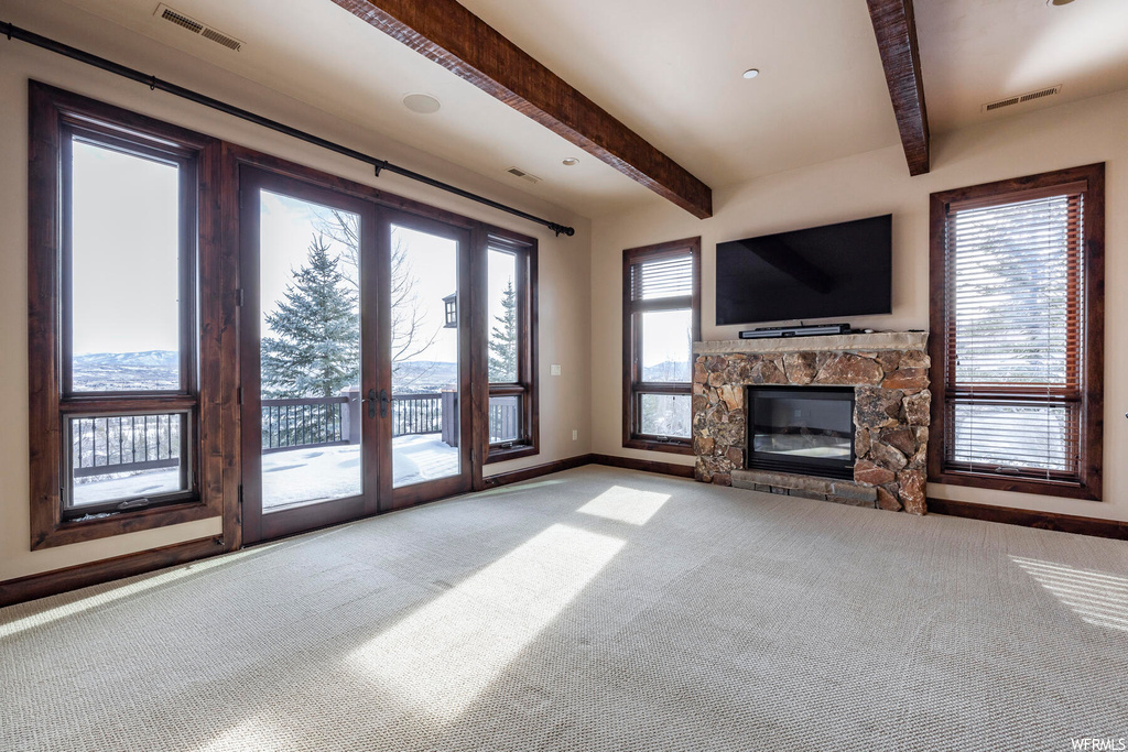 Unfurnished living room with light colored carpet, a fireplace, and beam ceiling