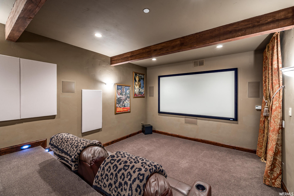 Carpeted home theater with beamed ceiling