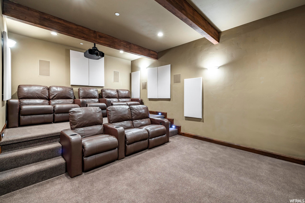 Carpeted home theater featuring beam ceiling