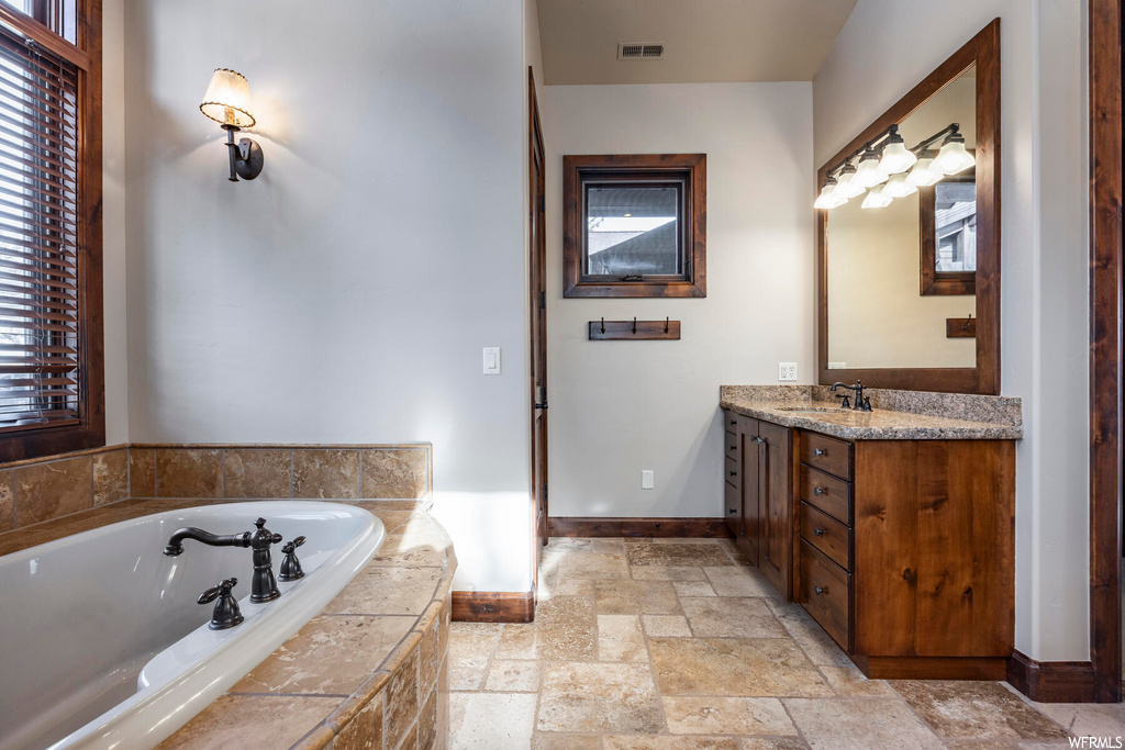 Bathroom with a relaxing tiled bath, tile floors, and vanity with extensive cabinet space