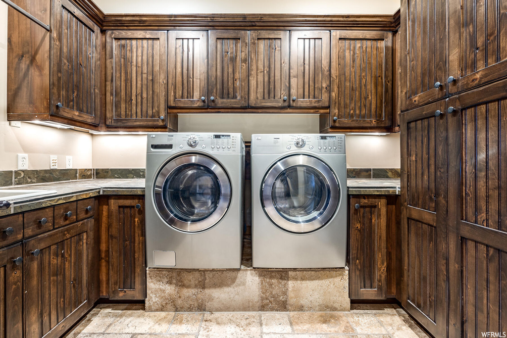 Laundry room featuring washing machine and clothes dryer, cabinets, and light tile floors
