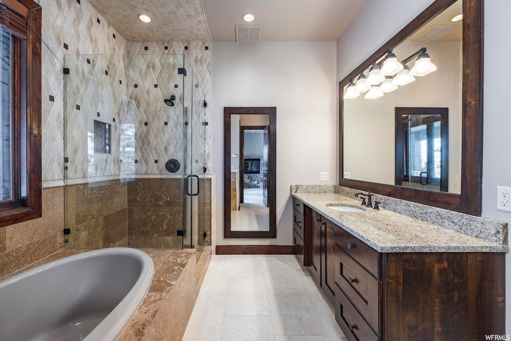 Bathroom featuring separate shower and tub, tile floors, and oversized vanity
