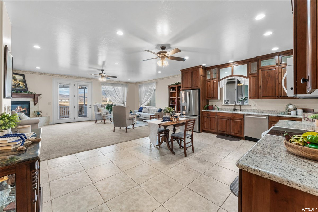 Kitchen featuring sink, appliances with stainless steel finishes, light stone countertops, ceiling fan, and light tile floors