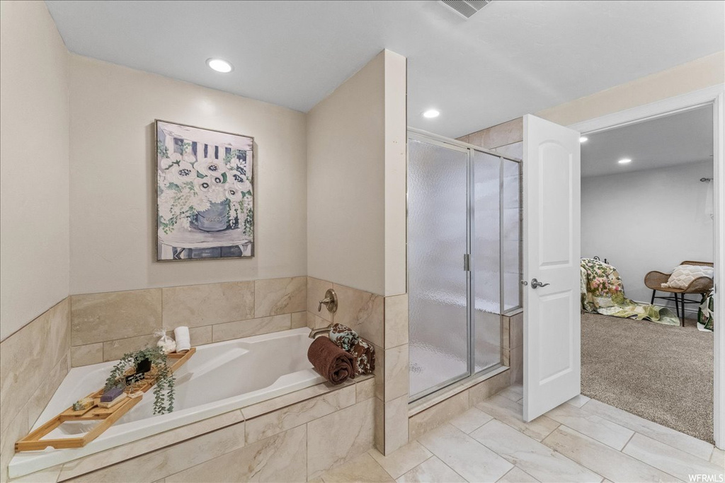 Bathroom featuring shower with separate bathtub and tile floors