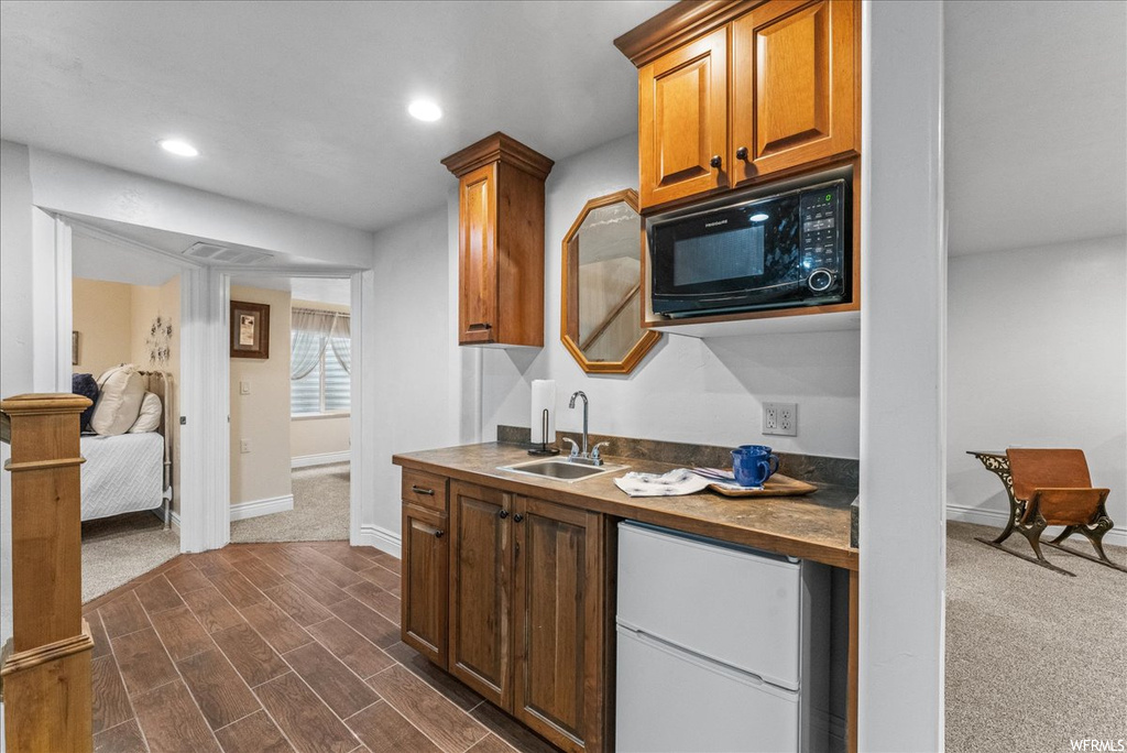 Kitchen with dark hardwood / wood-style flooring, sink, ornate columns, and black microwave