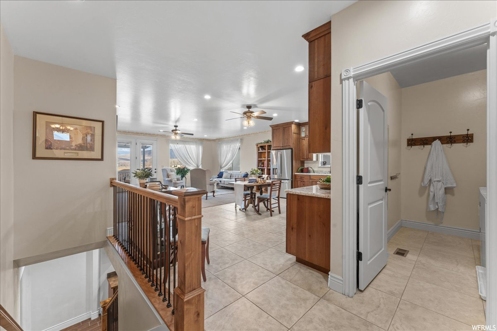 Kitchen featuring light tile floors, kitchen peninsula, stainless steel fridge with ice dispenser, and ceiling fan