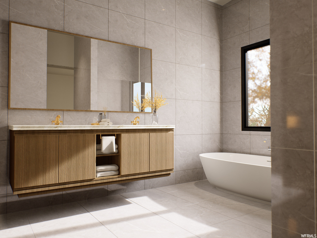 Bathroom featuring tile floors, tile walls, dual vanity, and a tub
