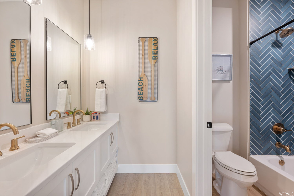Full bathroom featuring shower / bathing tub combination, toilet, double sink vanity, and hardwood / wood-style flooring