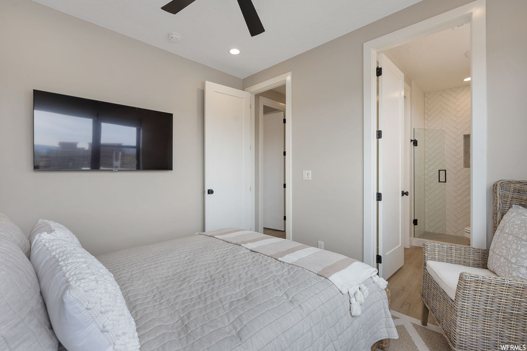 Bedroom with light wood-type flooring, ensuite bathroom, and ceiling fan
