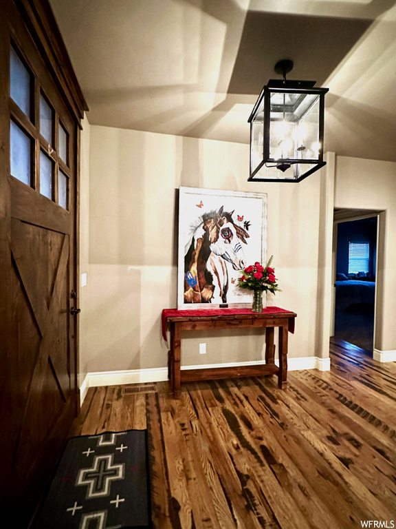 Hallway with dark hardwood / wood-style floors and a chandelier