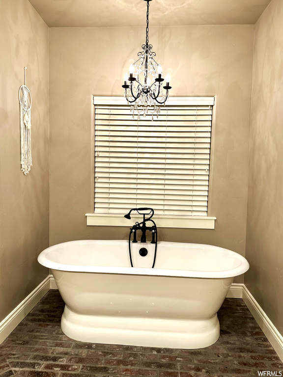 Bathroom featuring a notable chandelier and a bath