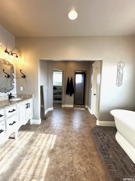 Bathroom featuring tile floors, a bath to relax in, and vanity with extensive cabinet space