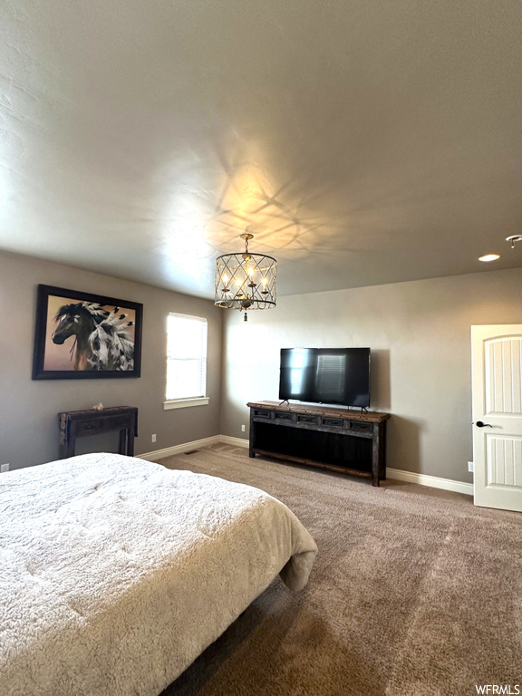 Carpeted bedroom with an inviting chandelier