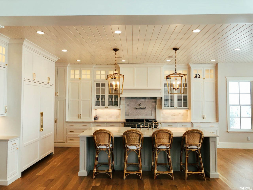 Kitchen with a center island with sink, dark hardwood / wood-style floors, and decorative light fixtures