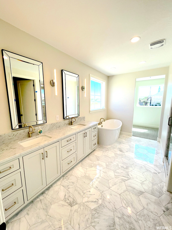 Bathroom with dual vanity, plenty of natural light, tile floors, and a bathing tub