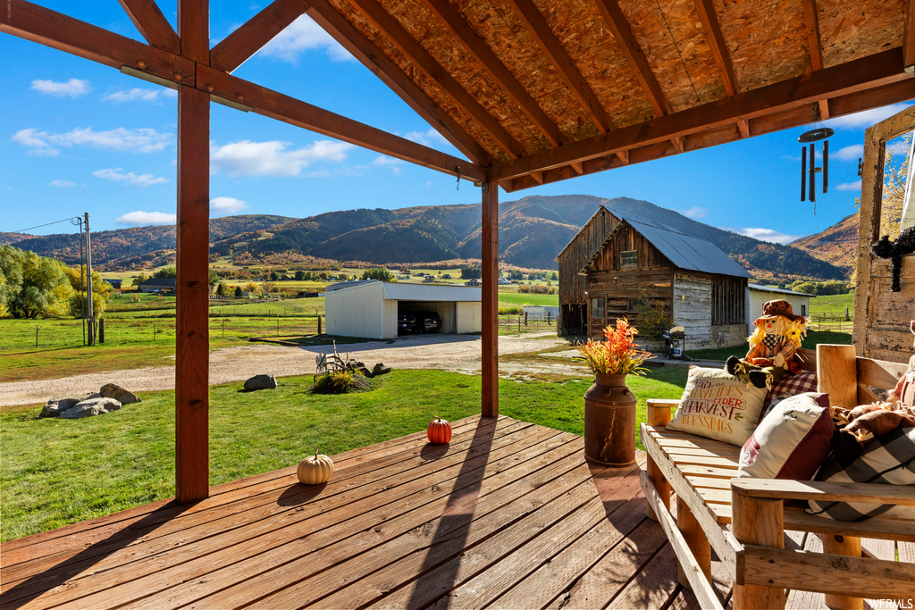 Deck with a storage shed, a mountain view, and a lawn