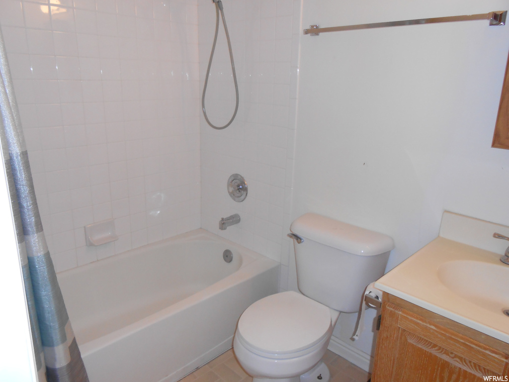 Full bathroom featuring shower / bath combination with curtain, toilet, and vanity