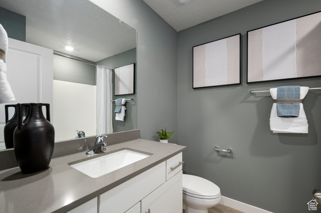 Bathroom featuring vanity with extensive cabinet space, a textured ceiling, and toilet