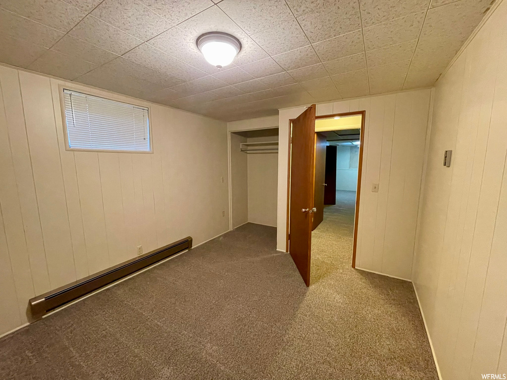 Basement with baseboard heating and light carpet