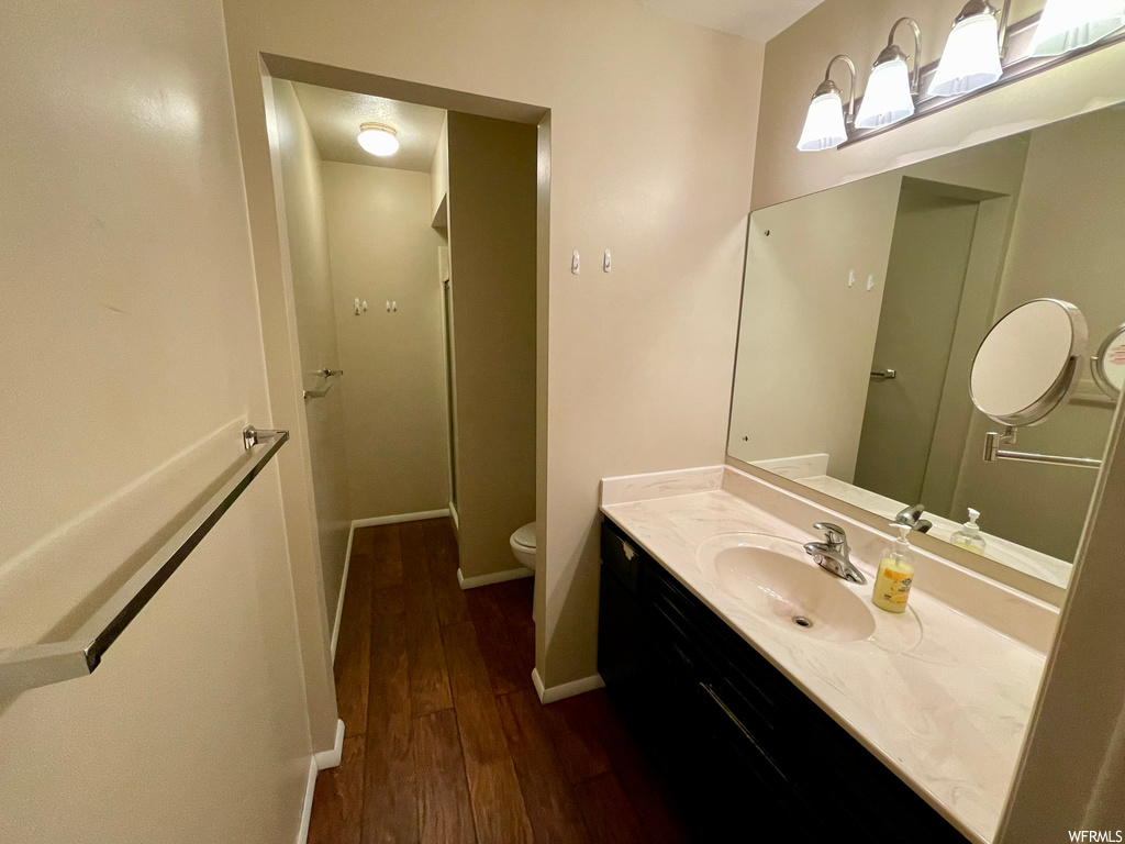 Bathroom with toilet, oversized vanity, and hardwood / wood-style floors