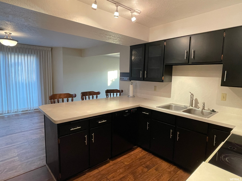 Kitchen with dark hardwood / wood-style flooring, track lighting, and kitchen peninsula