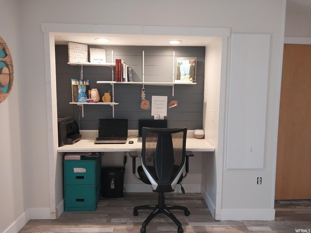 Home office featuring dark hardwood / wood-style flooring and built in desk