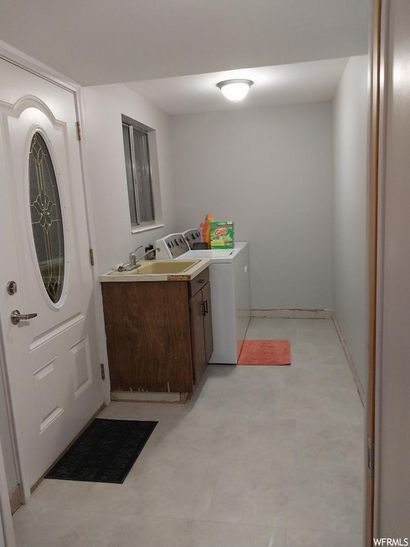 Laundry room featuring light tile flooring, cabinets, and washing machine and dryer
