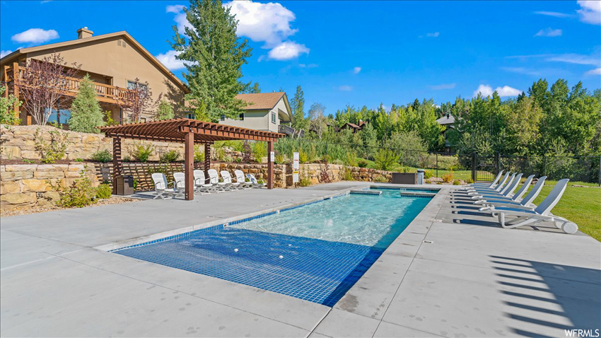View of pool featuring a pergola, pool water feature, and a patio