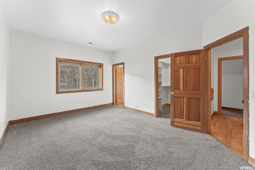 Unfurnished bedroom with a spacious closet, a closet, and light hardwood / wood-style floors